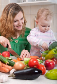 Mother with toddler preparing organic vegetables.